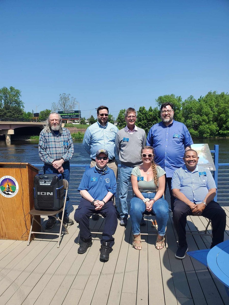 dncap team sitting together and posing for a picture on the deck with river behind them.